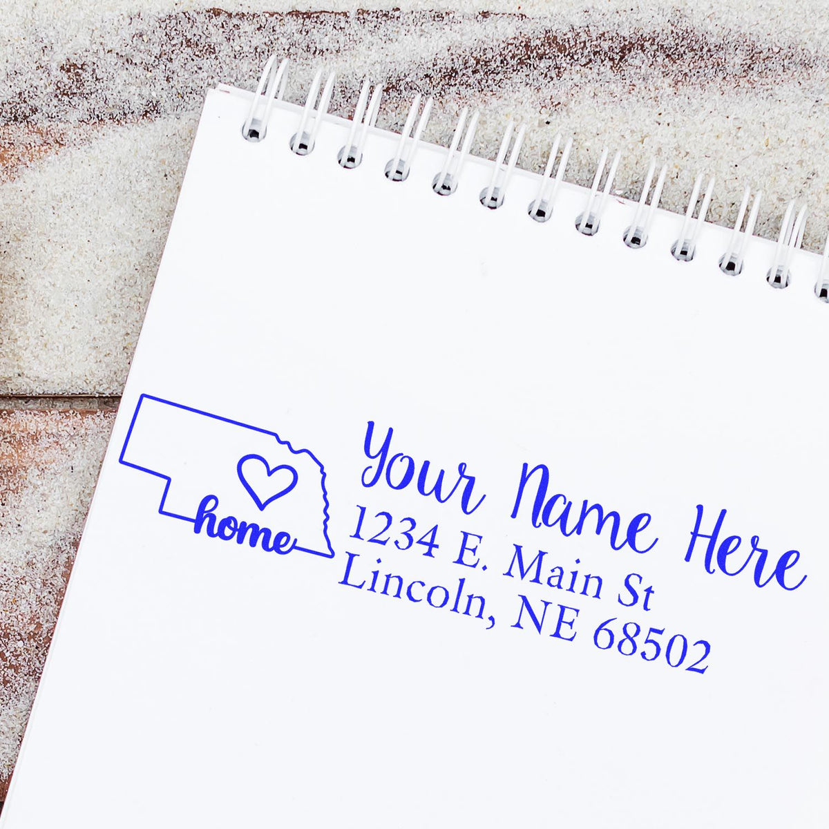 Custom Nebraska home address rubber stamp with heart design, stamped on a notebook page for personalized mailing.