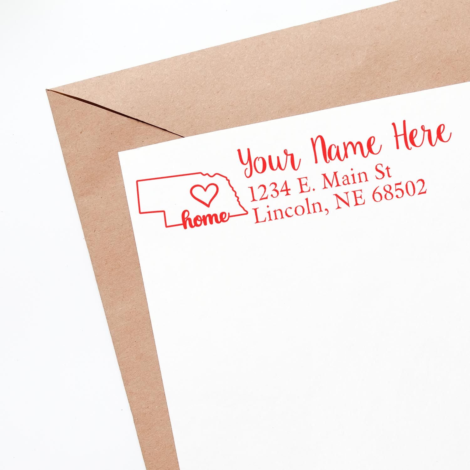 Custom return address rubber stamp with Nebraska home design and heart, shown on an envelope for mailing.