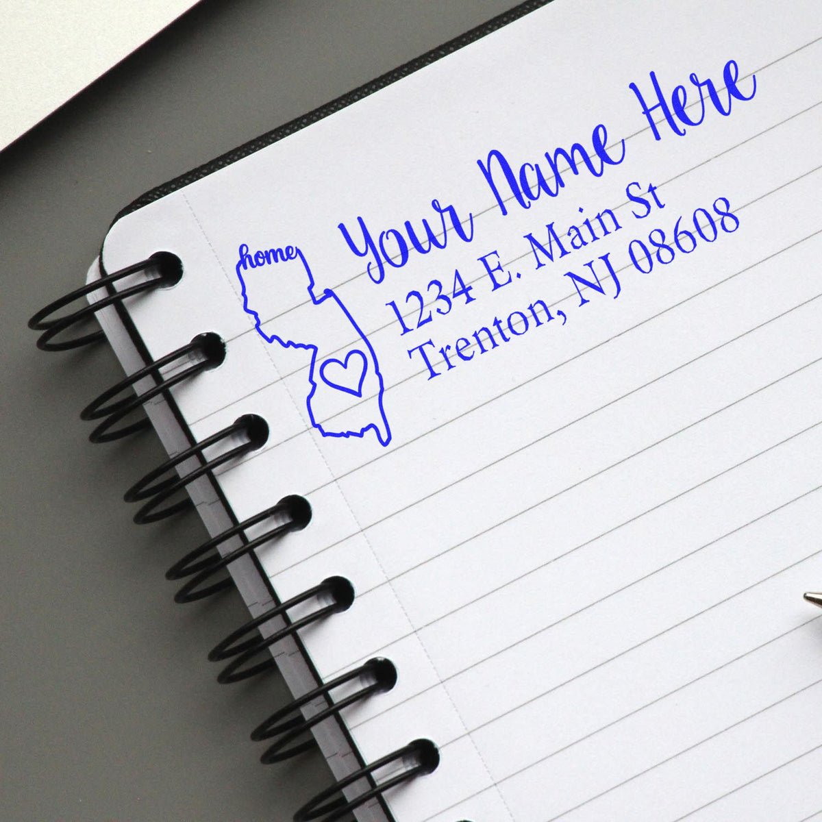 Custom rubber address stamp impression on notebook page with name and return address for envelopes.
