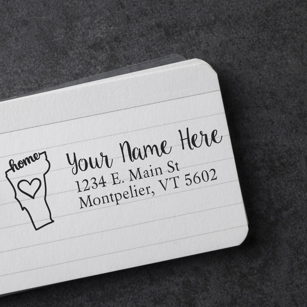 Personalized return address rubber stamp on lined notebook paper with name, address, and Vermont state icon.