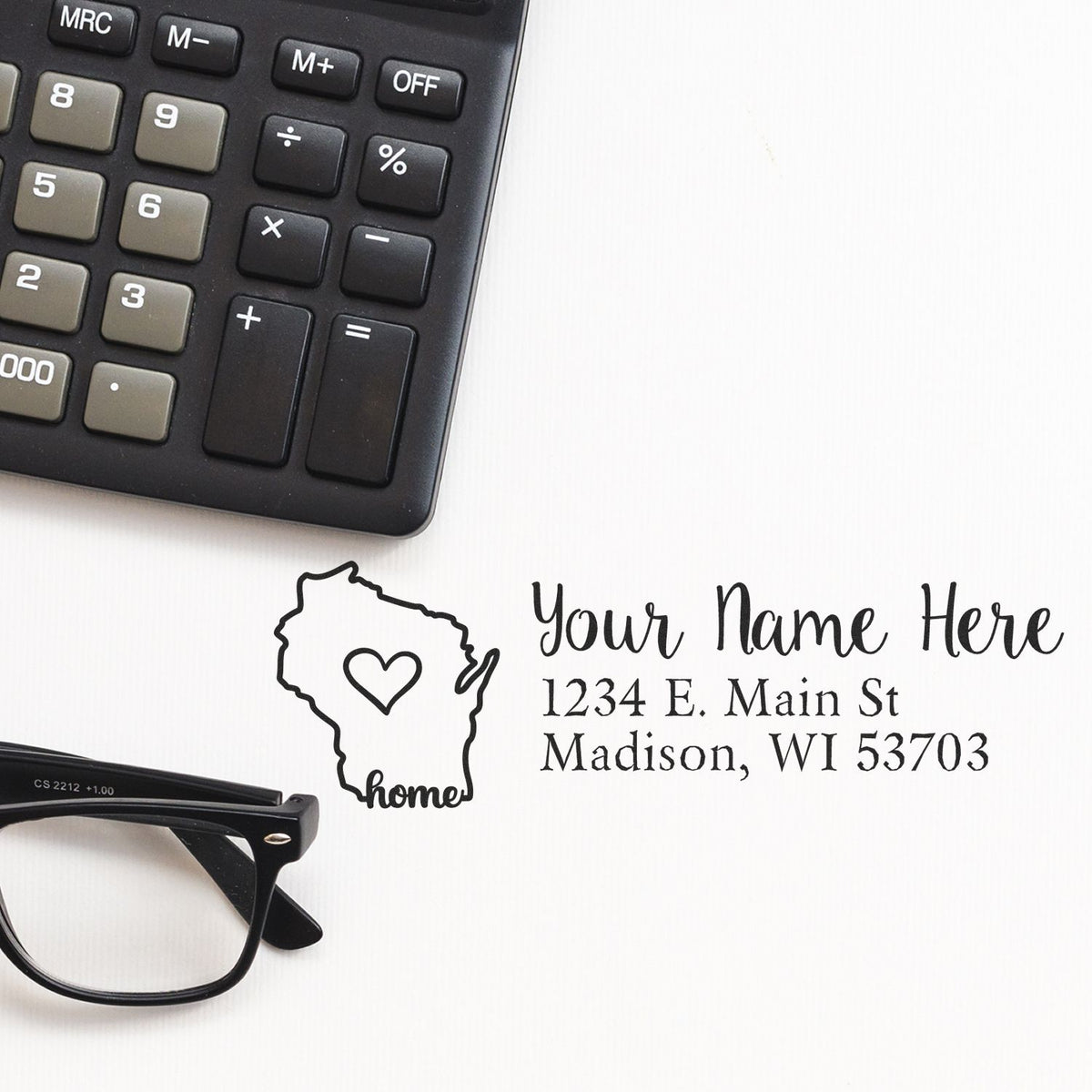 Custom address rubber stamp with Wisconsin home design, name, and Madison, WI address beside calculator and glasses.