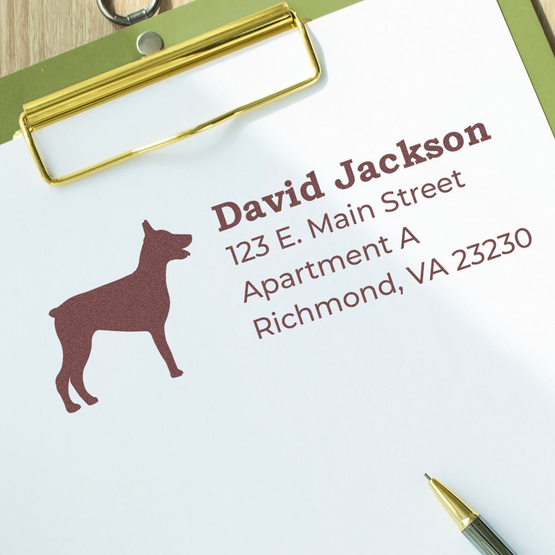 Custom address rubber stamp with dog logo and name on clipboard for mail, packaging, and pet business branding.