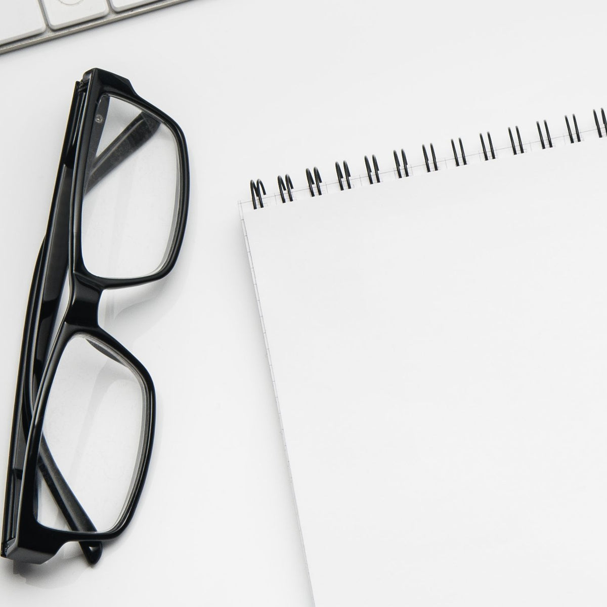 Glasses and spiral notebook on a clean desk for custom rubber stamp design, office planning, and business branding.