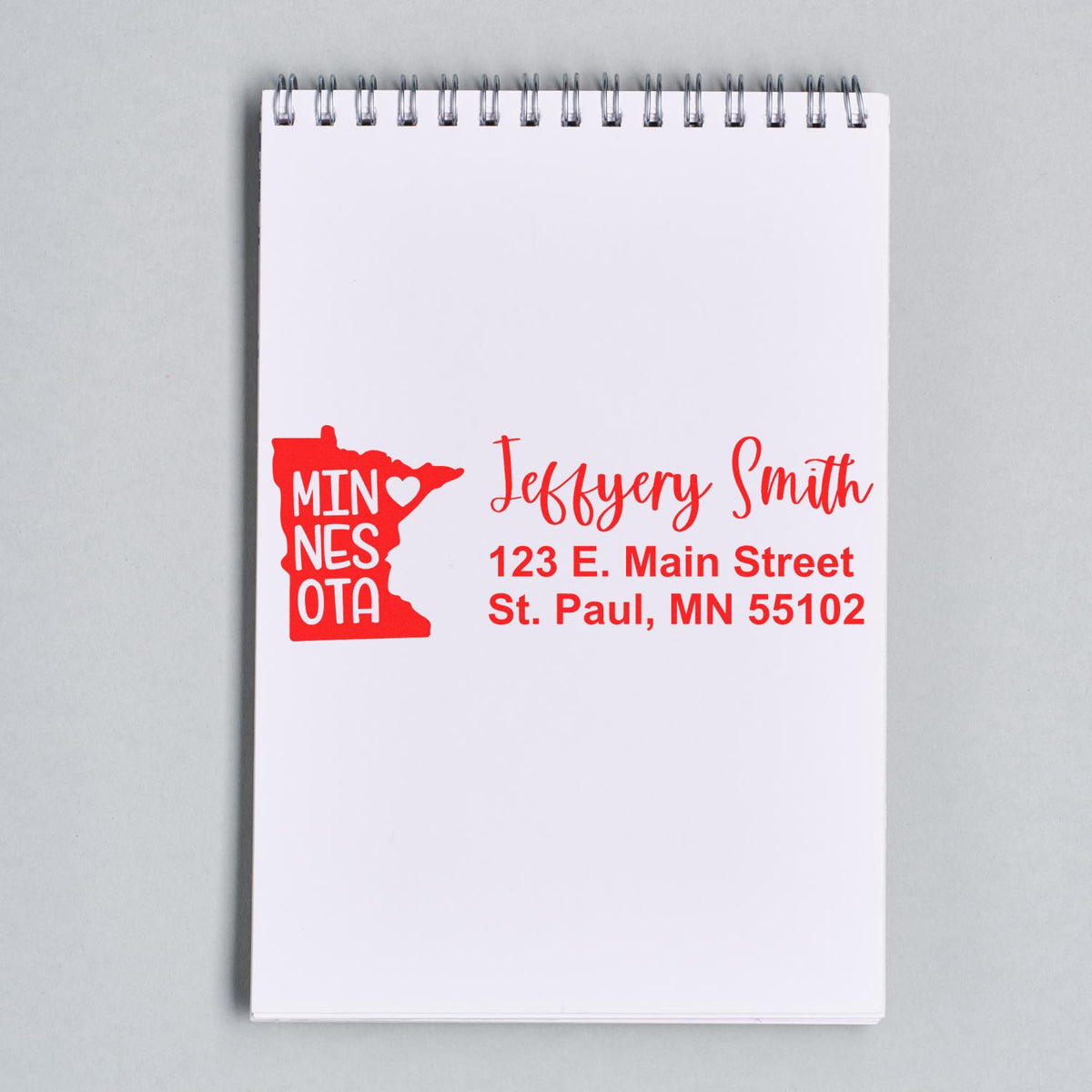 Custom Minnesota rubber stamp with name and return address printed on notepad, featuring state outline logo.