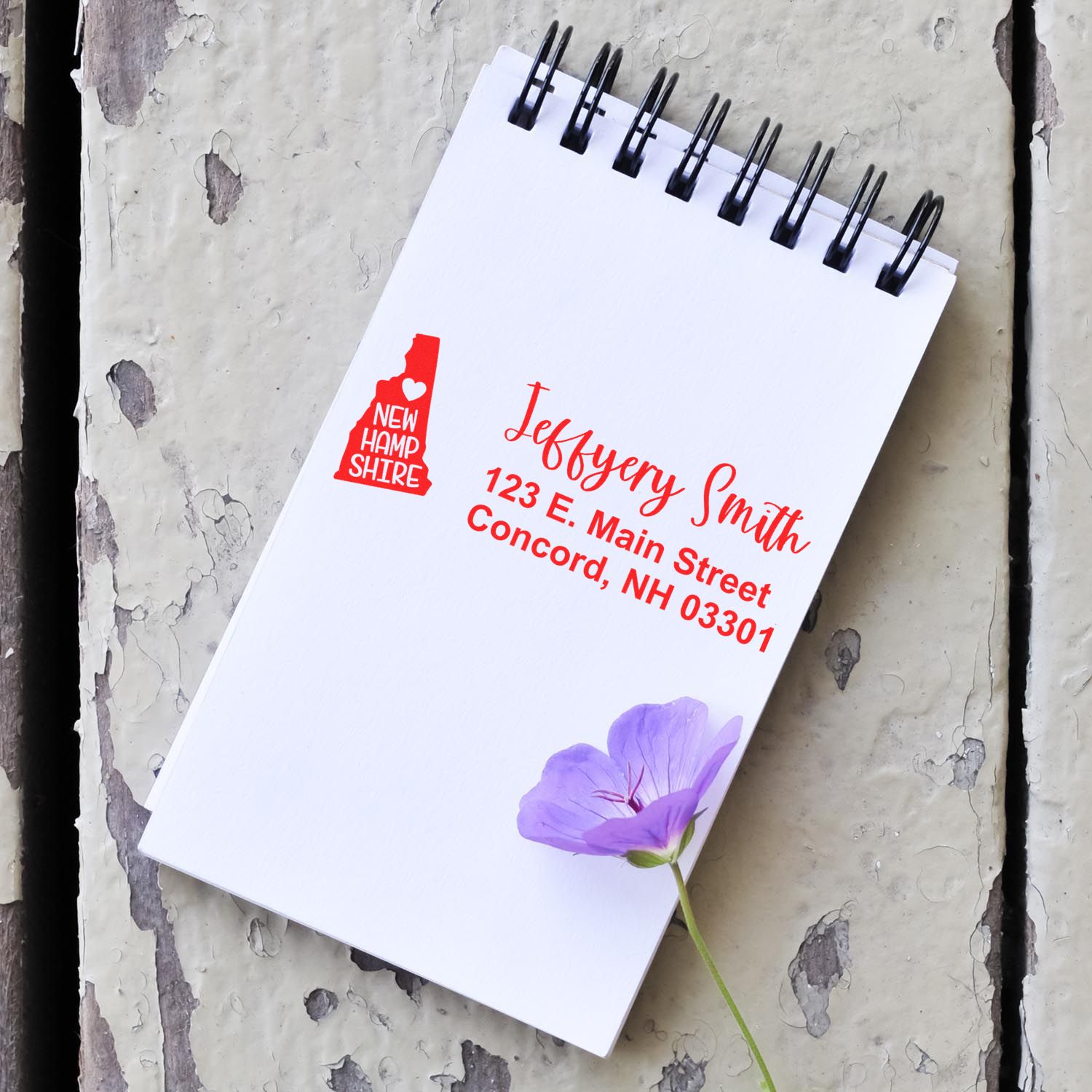 Custom address rubber stamp for personalized stationery with New Hampshire state logo on a spiral notebook.