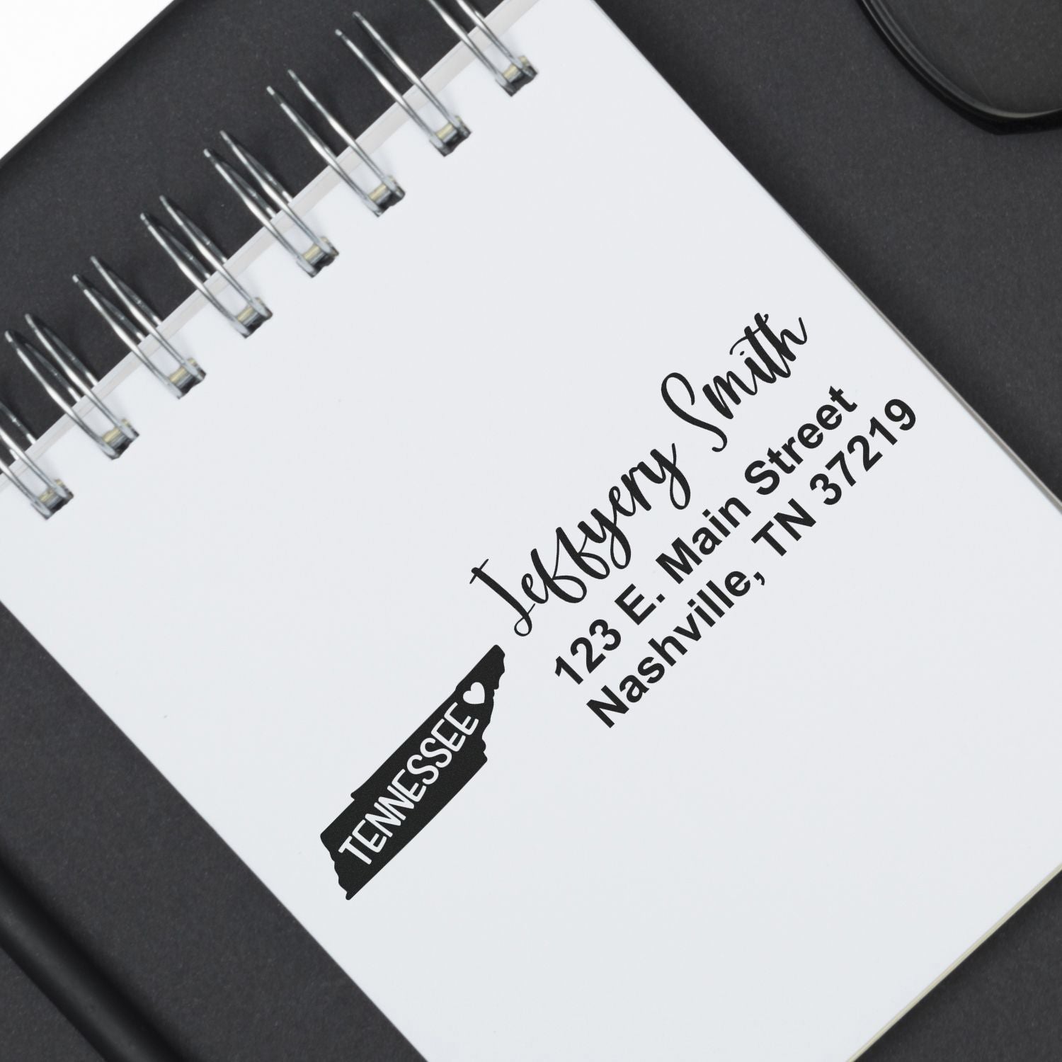 Custom rubber address stamp with Tennessee silhouette, name, and Nashville address on a notebook for personalized stationery.