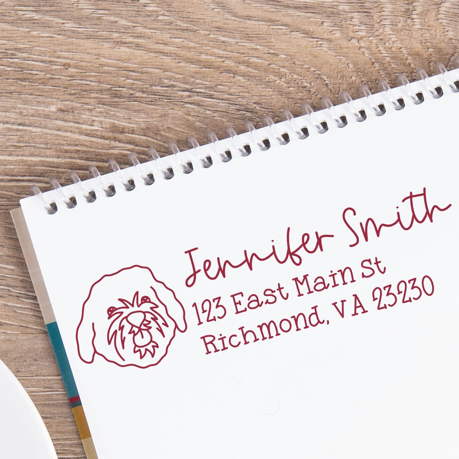Custom rubber address stamp with dog logo for Jennifer Smith, 123 East Main St, Richmond, VA 23230 on notebook paper.