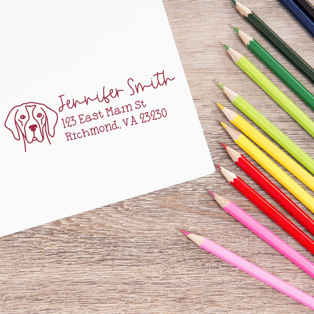 Custom dog address rubber stamp for personalized stationery, stamped on paper beside colorful pencils.
