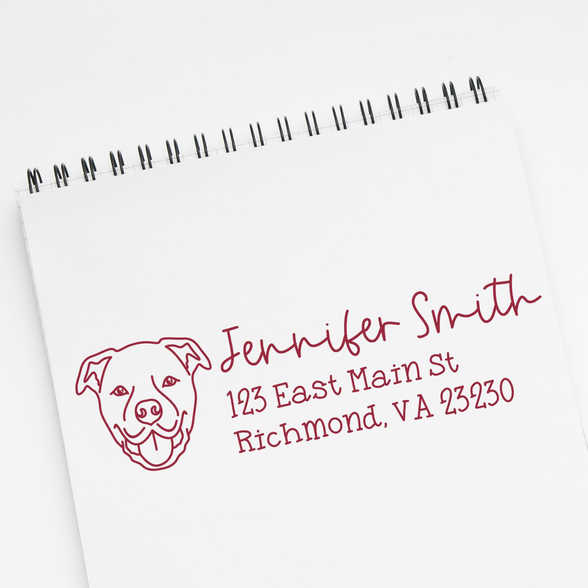 Personalized rubber address stamp with dog logo for Jennifer Smith, Richmond VA, shown on a notebook page.