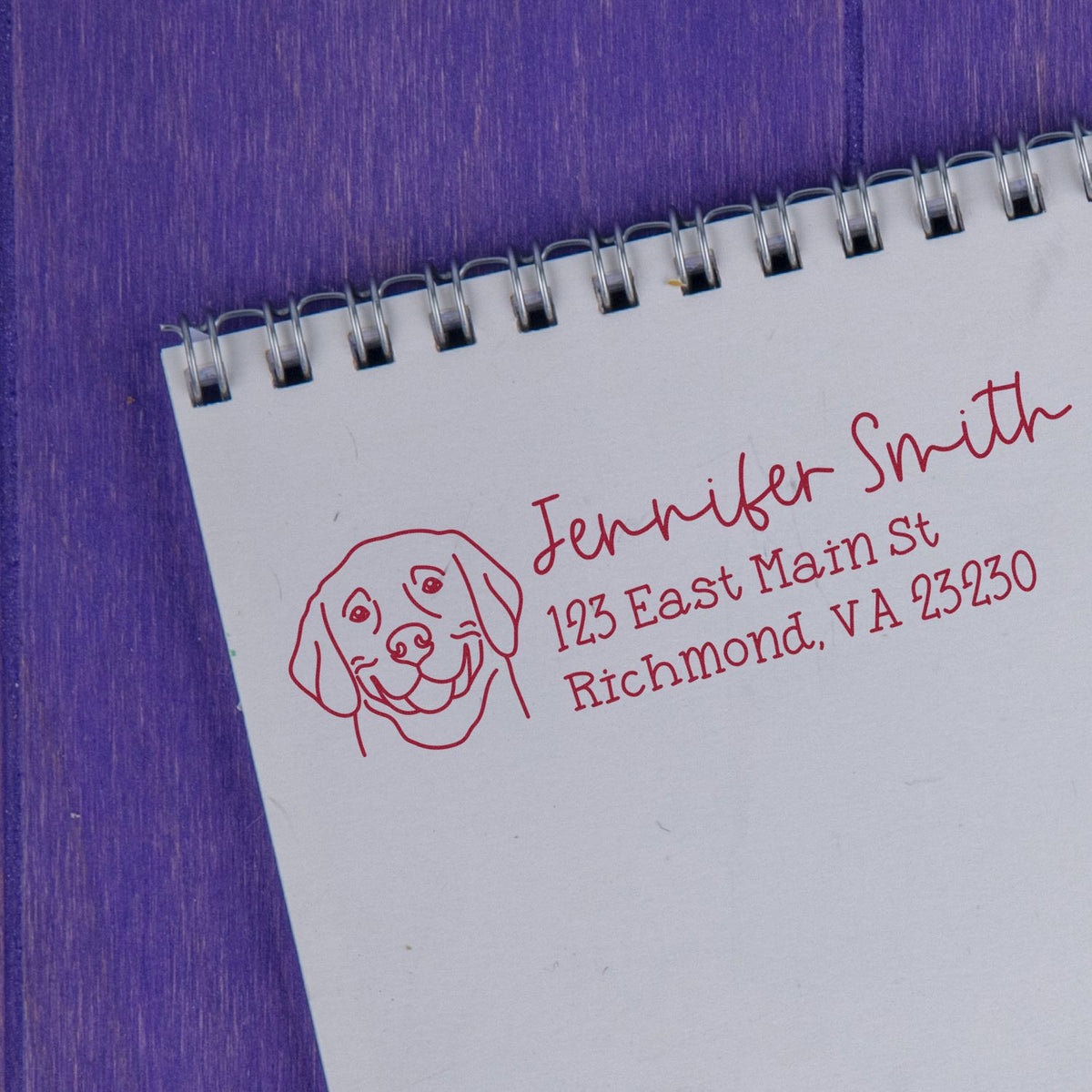 Custom dog address rubber stamp for Jennifer Smith, 123 East Main St, Richmond, VA 23230, on notebook paper.