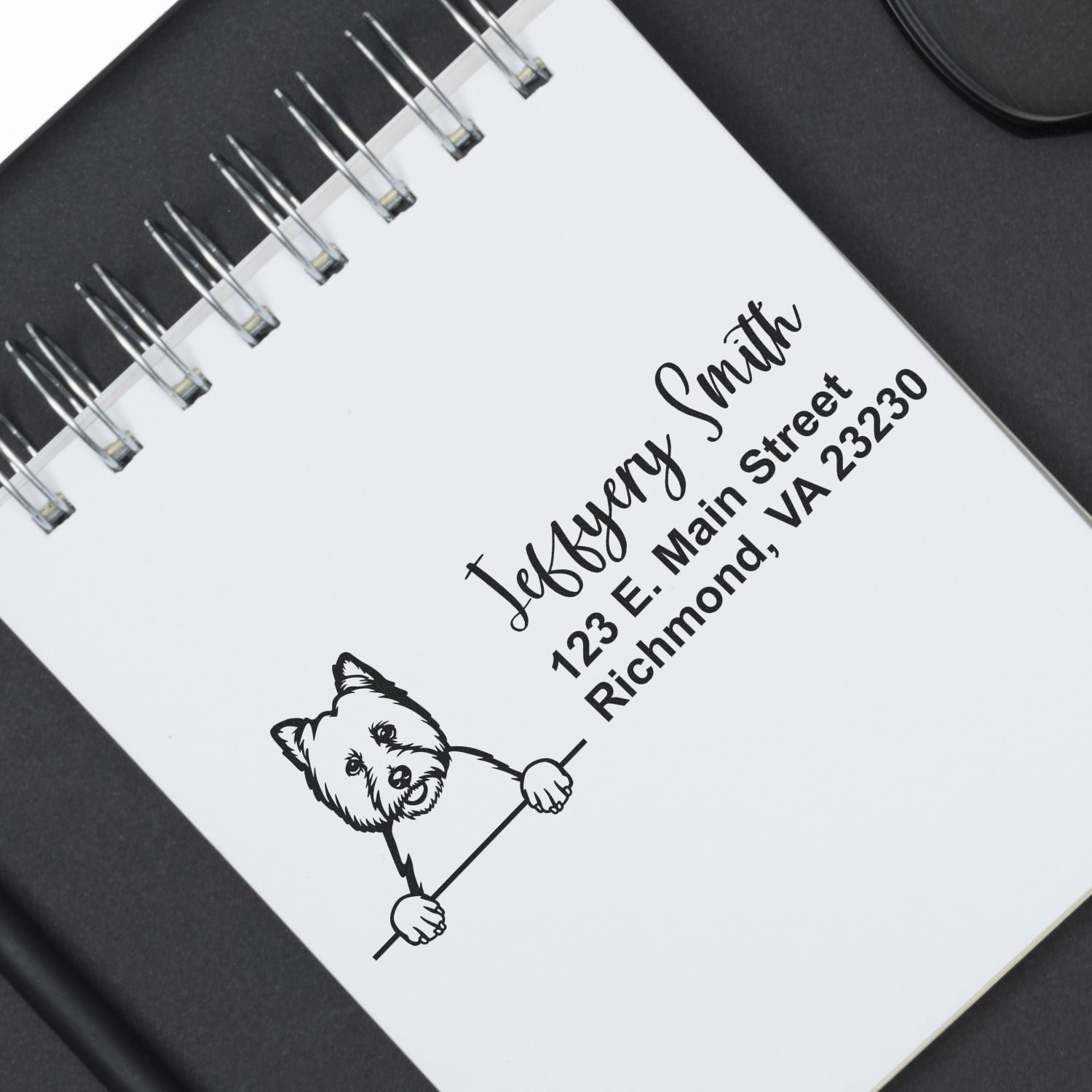 Custom return address rubber stamp with dog logo and Jeffery Smith address, printed on a spiral notebook.