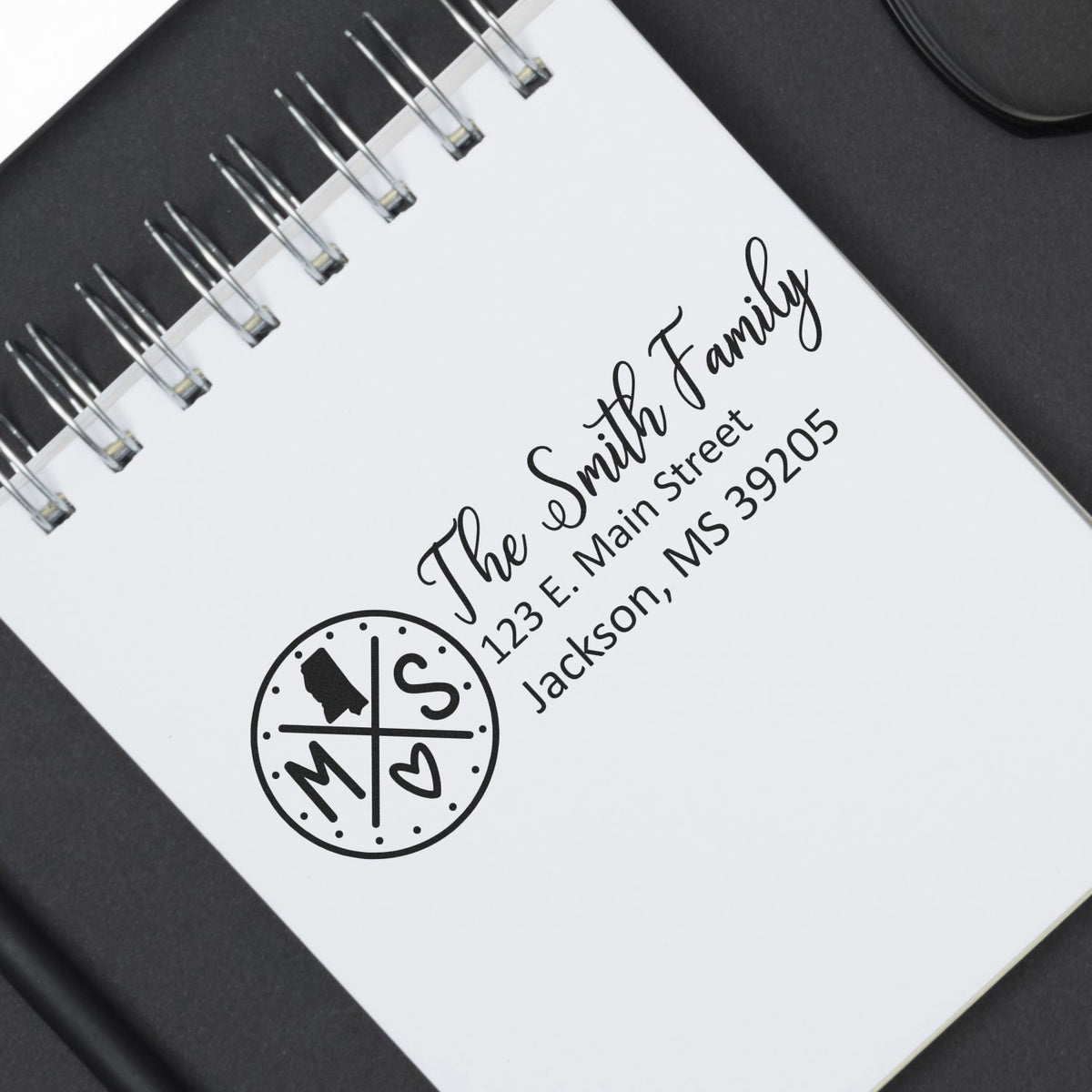 Personalized family return address rubber stamp with monogram, shown on a spiral notebook cover.