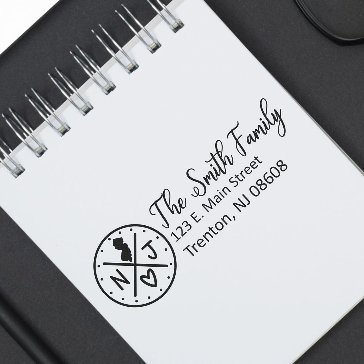 Custom family address rubber stamp with monogram logo on notebook, featuring The Smith Family and New Jersey address.
