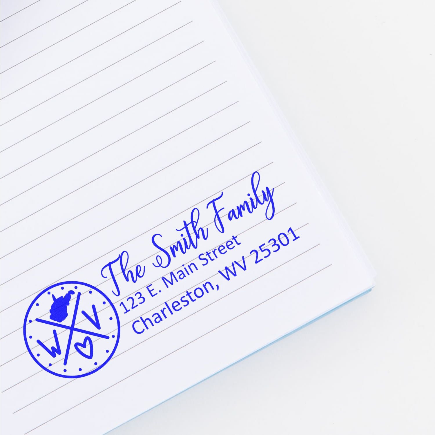 Custom family return address rubber stamp with monogram logo, The Smith Family, Charleston, WV, on lined paper.