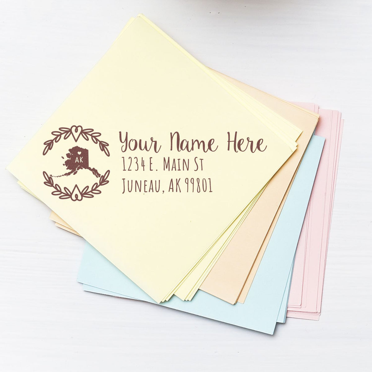 Personalized return address rubber stamp with Alaska design, shown on pastel envelopes for weddings, business mail, or stationery.