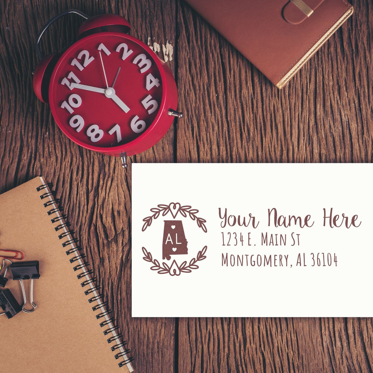 Custom return address rubber stamp with Alabama monogram, name, and address mockup on a rustic desk.