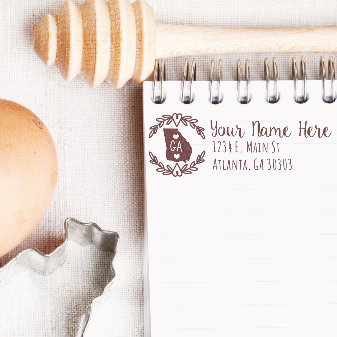 Custom return address rubber stamp mockup with Georgia state design, name, and address imprint on a notepad.