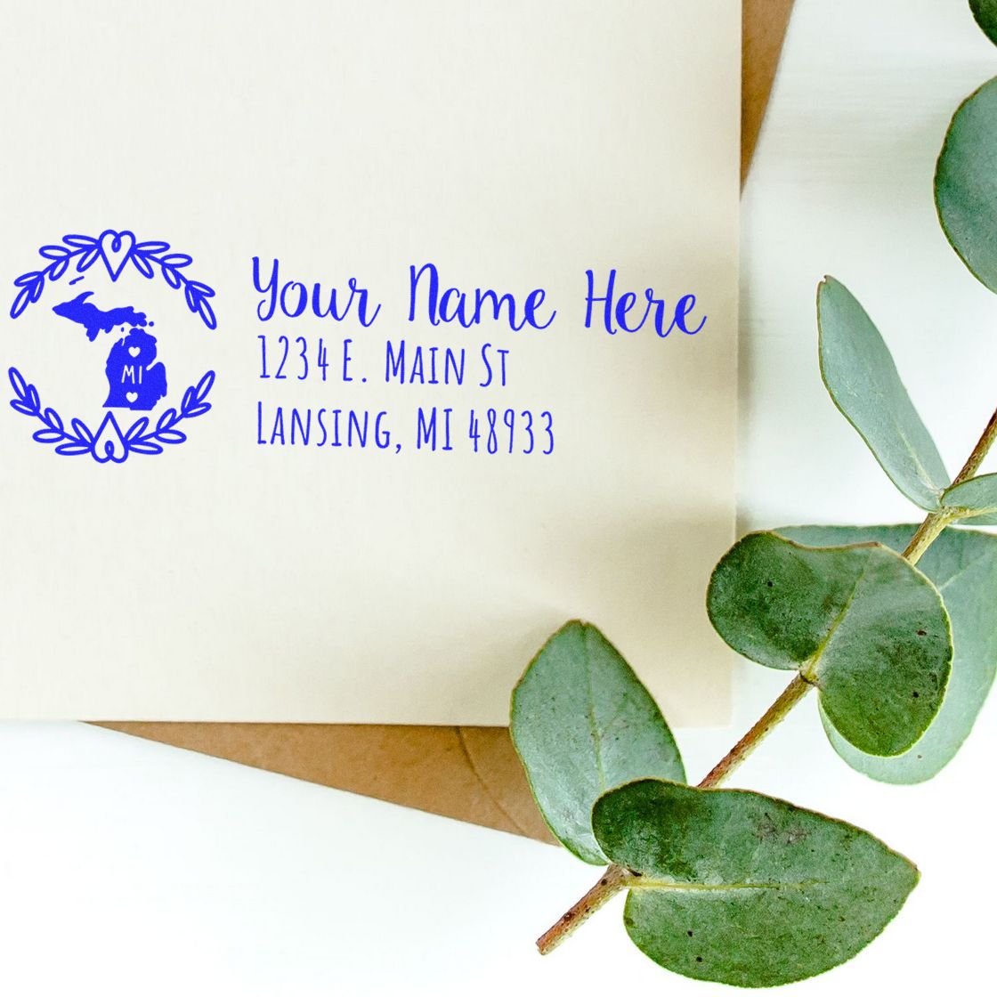 Personalized Michigan return address rubber stamp with floral wreath design on envelope, styled with eucalyptus greenery.