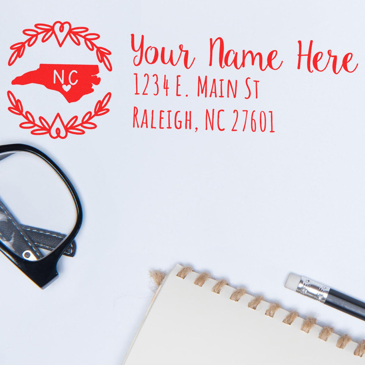 Personalized return address rubber stamp with North Carolina state design, floral wreath, name, and Raleigh NC address.