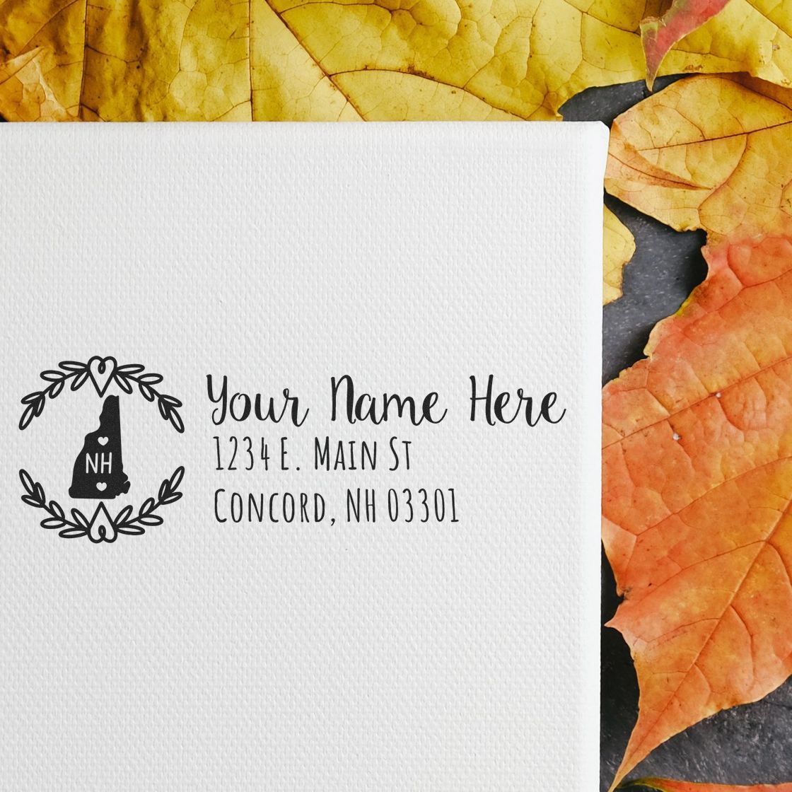 Custom return address rubber stamp with New Hampshire monogram on a white envelope, featuring name and address in decorative script.