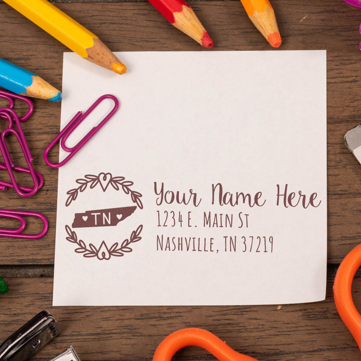 Custom Nashville return address rubber stamp with Tennessee design on paper, surrounded by colorful pencils and paperclips.