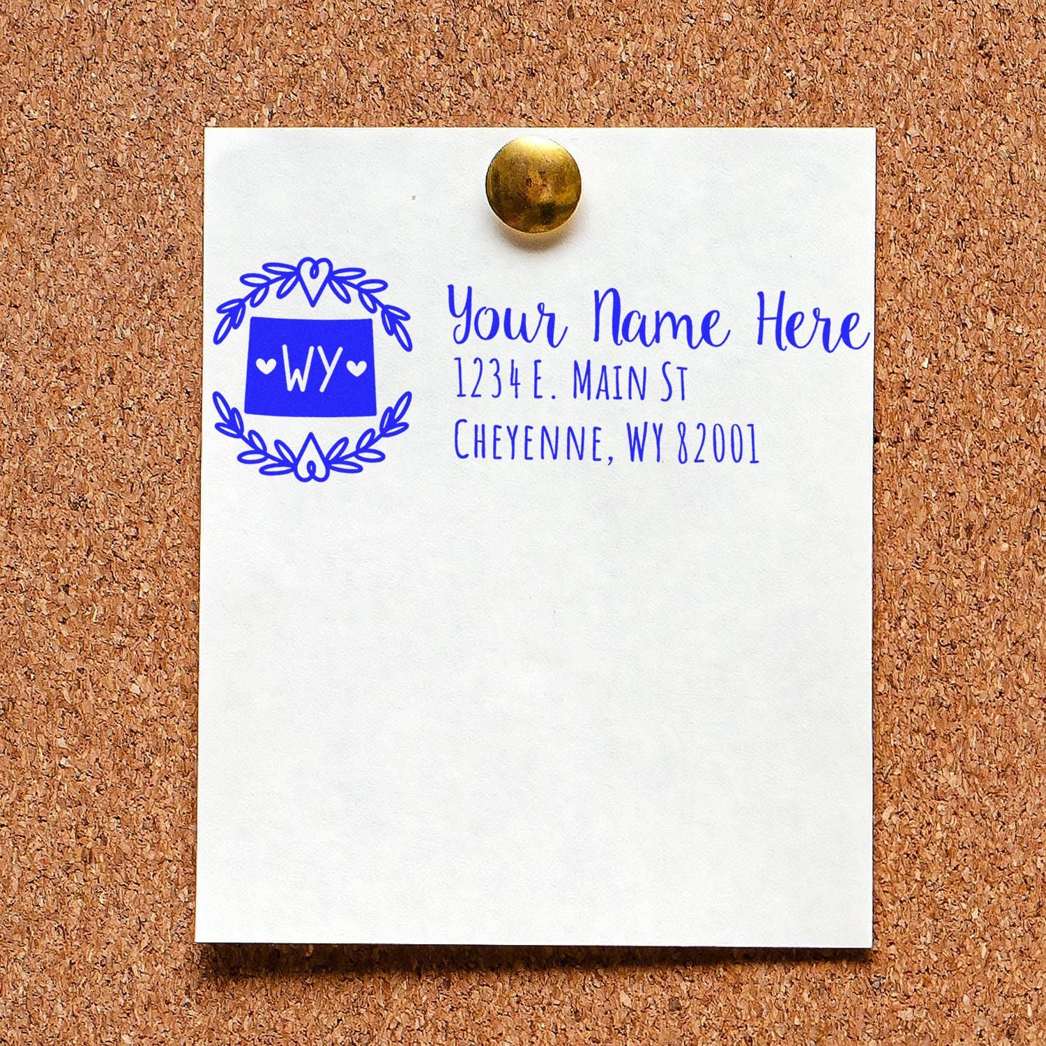 Personalized return address rubber stamp with Wyoming monogram, name, and address in blue ink on a pinned card.