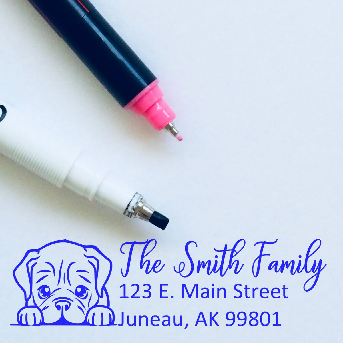 Custom address rubber stamp with dog logo, showing blue ink imprint for The Smith Family, 123 E. Main Street, Juneau, AK 99801.