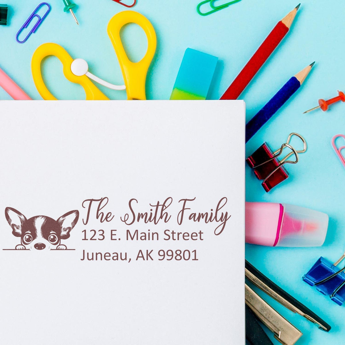 Custom personalized rubber stamp with family dog logo and return address on paper, surrounded by colorful stationery.