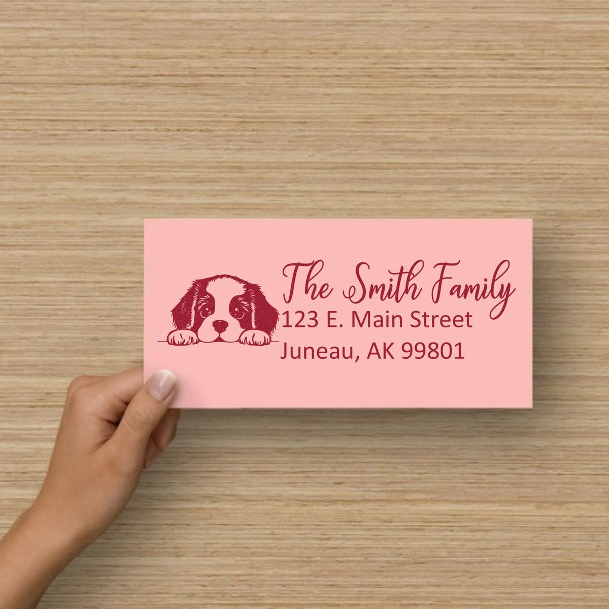 Custom dog family address stamp on pink card, featuring name, street address, and city for mailing.