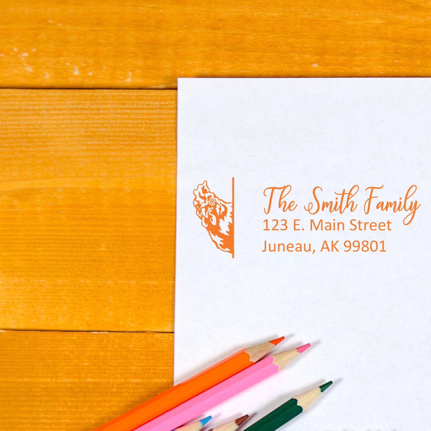 Custom rubber stamp return address with chicken illustration for The Smith Family, orange ink on stationery.