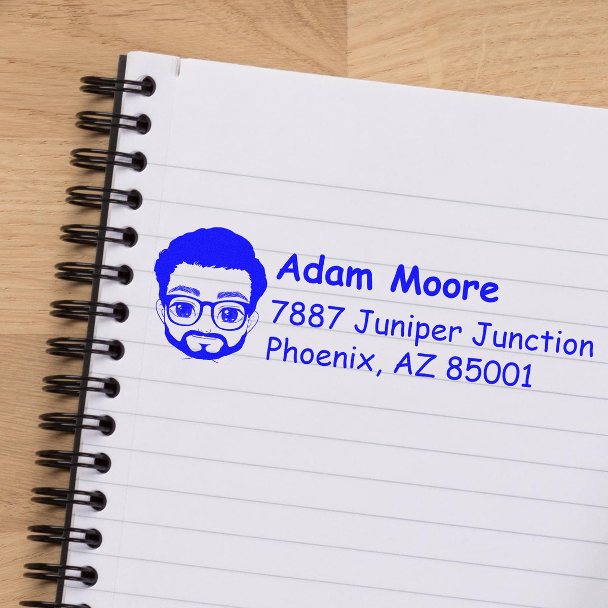 Custom rubber address stamp with avatar logo for Adam Moore, Phoenix, AZ, stamped on a notebook page.