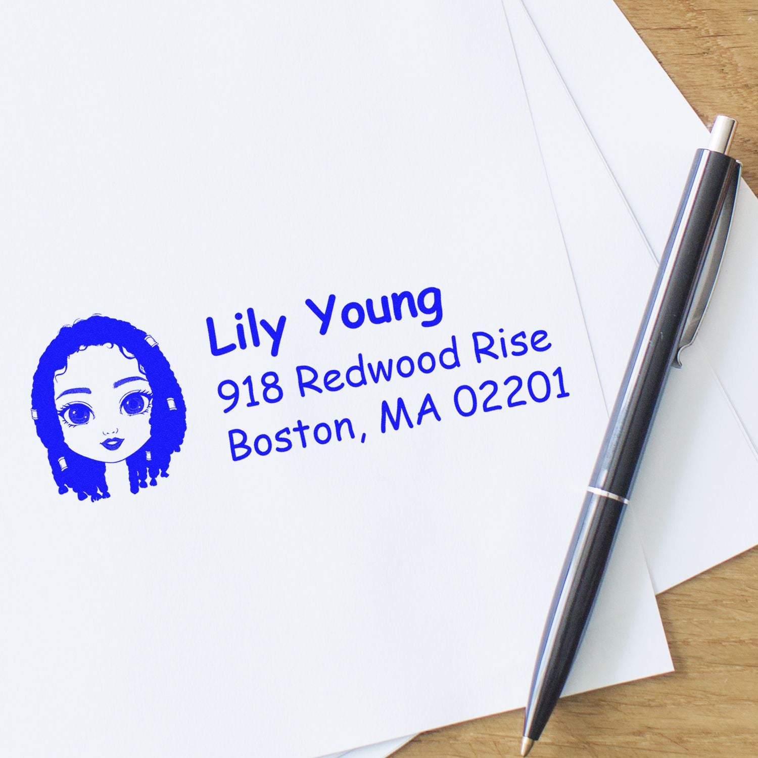 Personalized rubber address stamp with blue name and return address impression on envelope beside a pen.