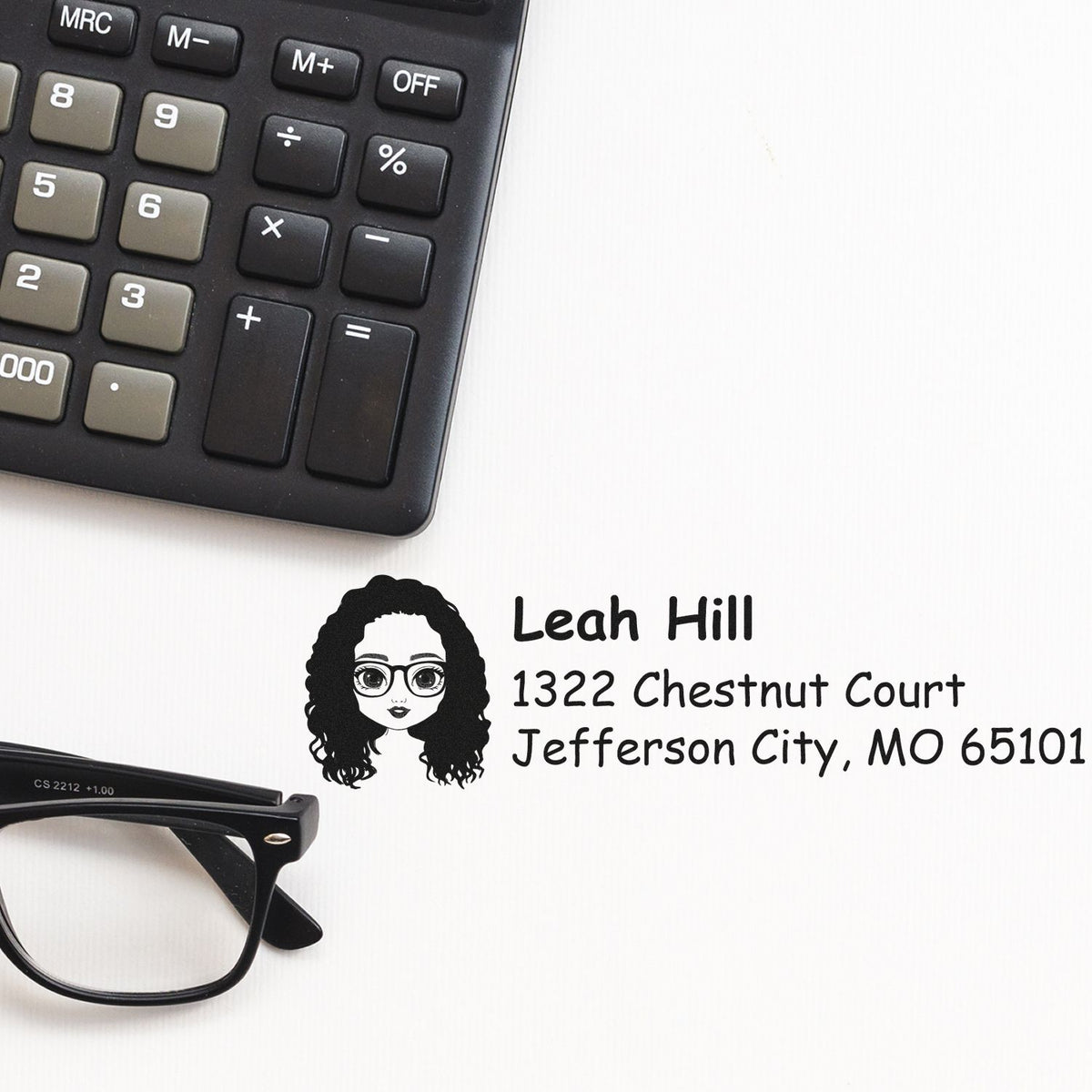 Custom return address rubber stamp with name and address, shown beside calculator and glasses for office use.