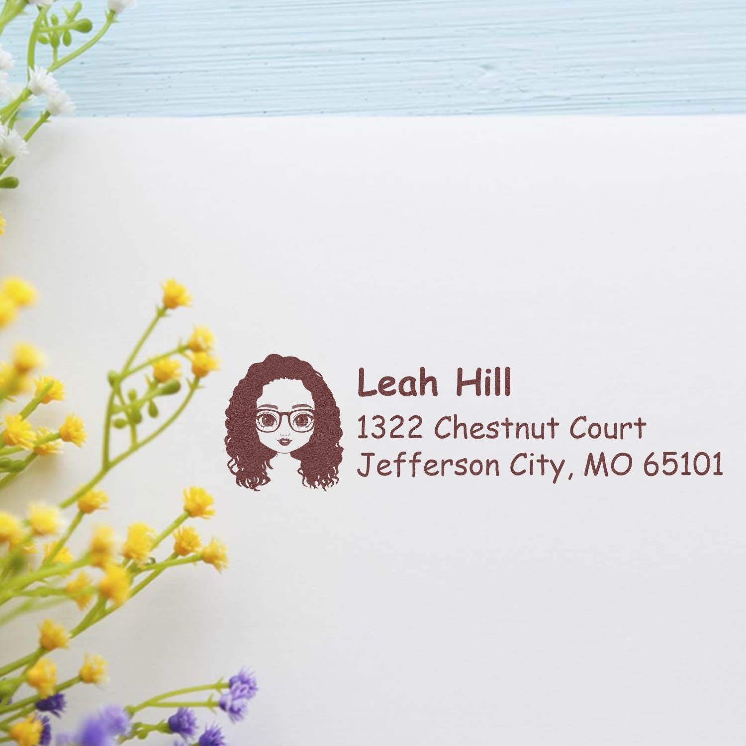 Custom return address rubber stamp with female portrait icon, name, and mailing address for envelopes and stationery.