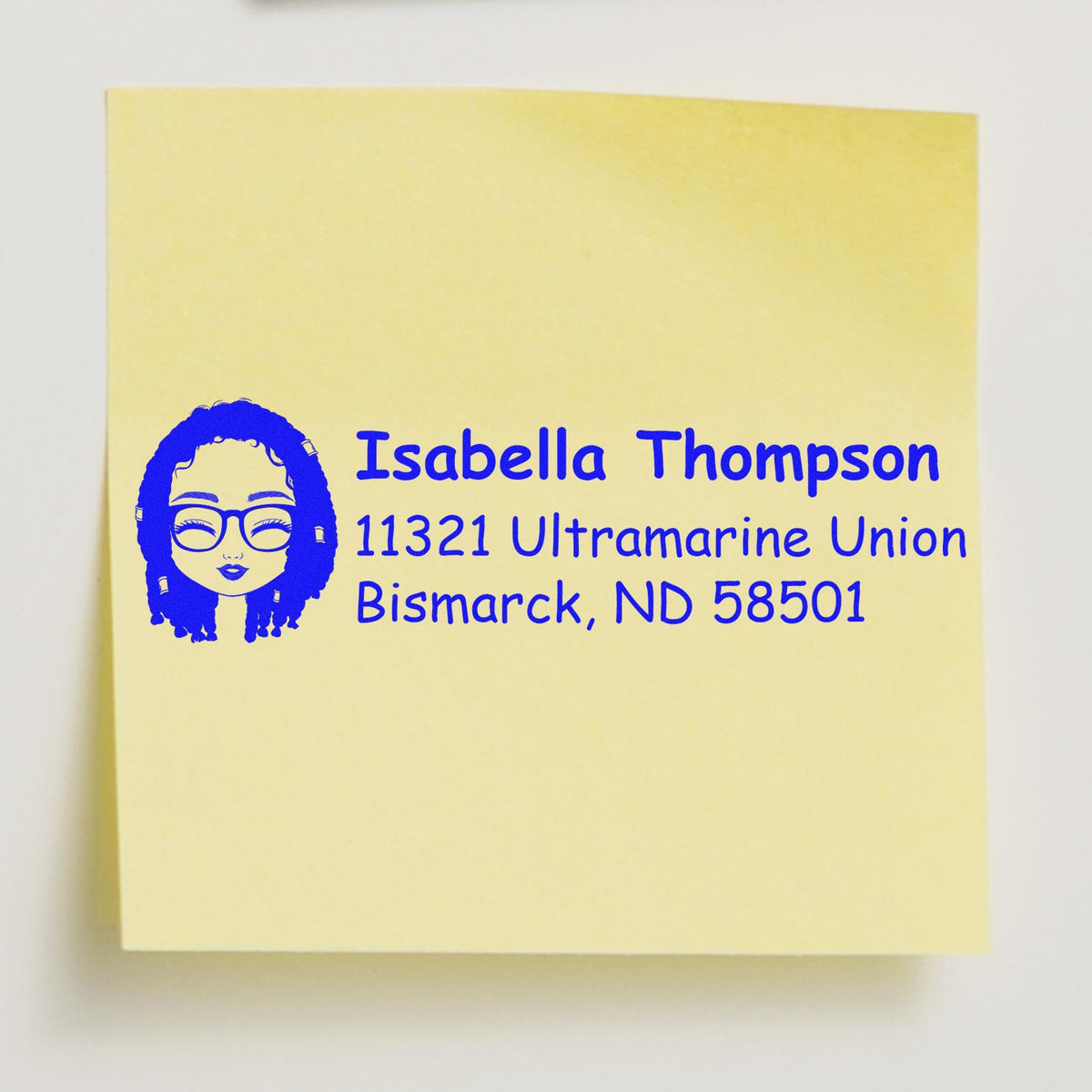 Custom rubber stamp return address with avatar for Isabella Thompson, Bismarck, ND 58501 on a yellow note.