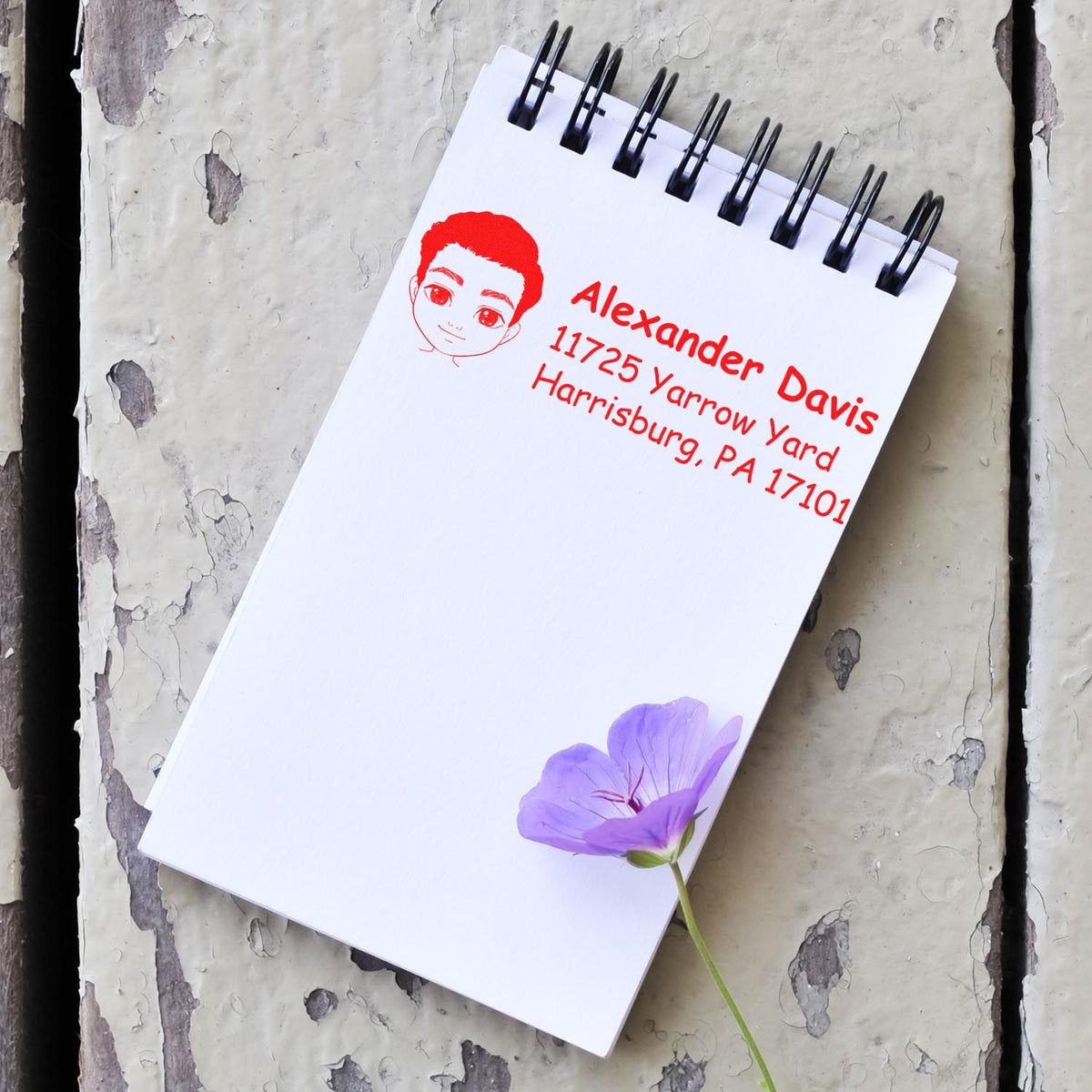 Personalized rubber stamp impression on a spiral notebook, featuring a custom name and address for mailing and crafts.