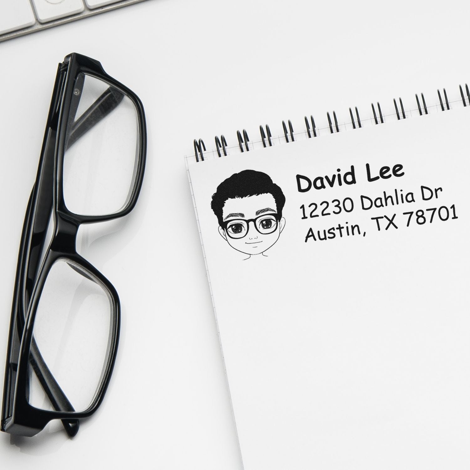 Custom rubber address stamp with cartoon portrait, name, and Austin TX address beside eyeglasses.