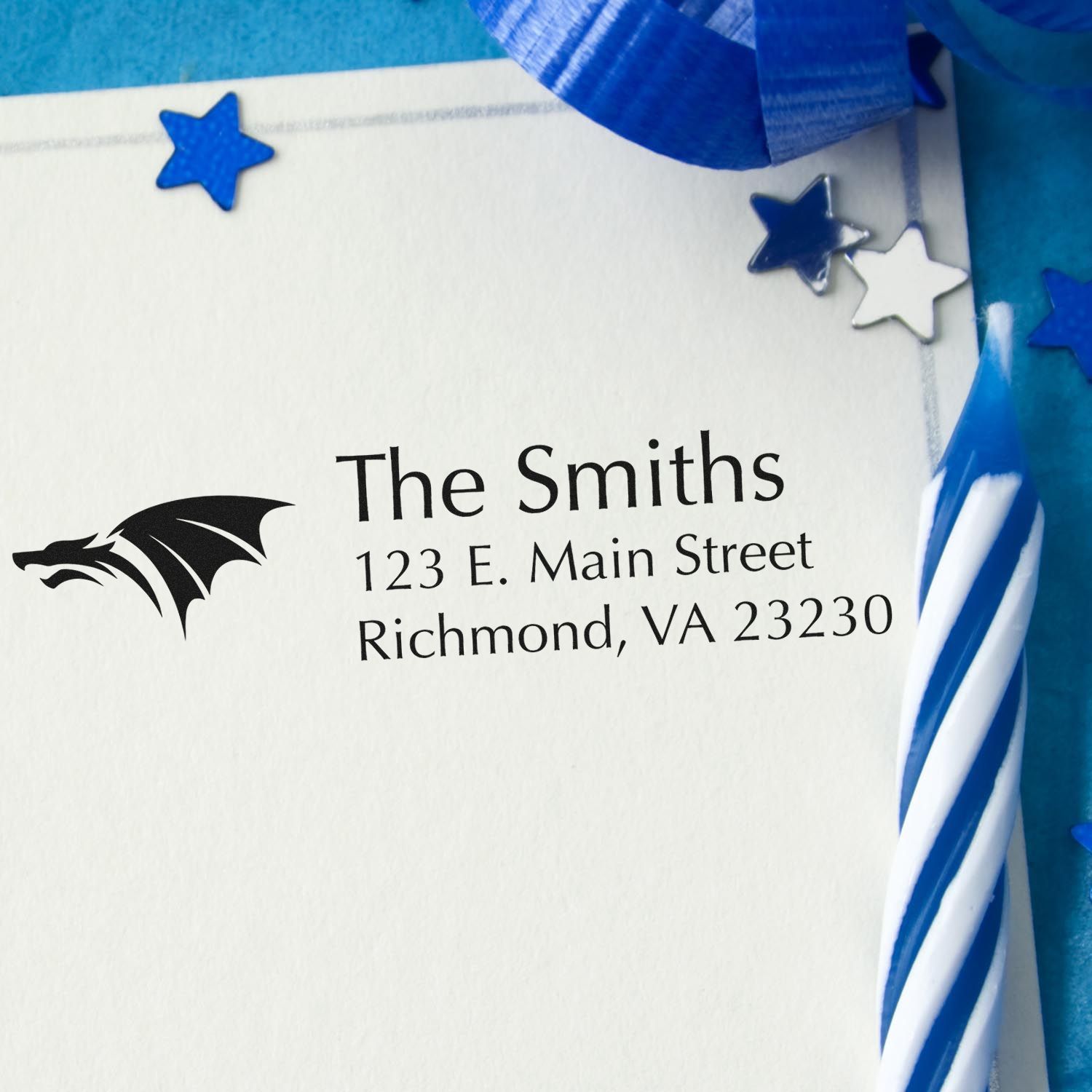 Custom return address rubber stamp with dragon logo for The Smiths, printed on an envelope with blue star and ribbon accents.