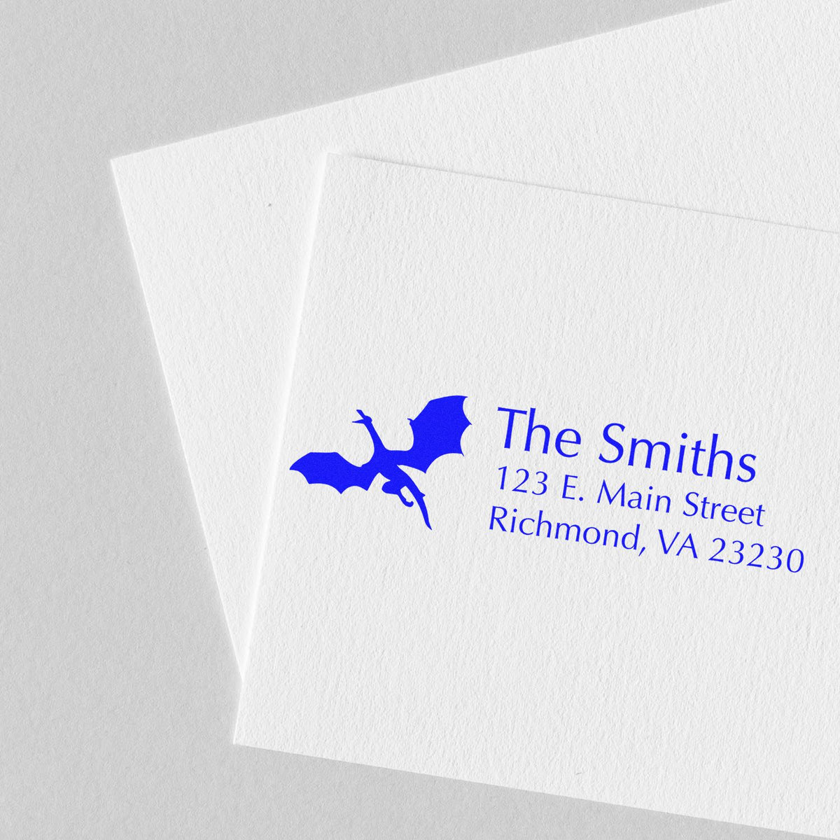 Custom blue address rubber stamp for The Smiths with dragon logo and Richmond, VA mailing address on white paper.