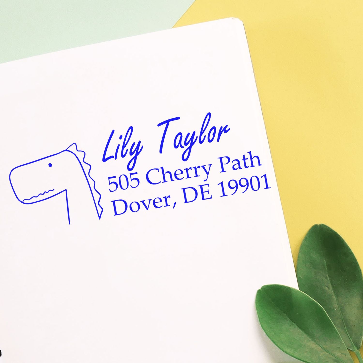 Custom return address rubber stamp for Lily Taylor, featuring a dinosaur icon and Dover, DE 19901.