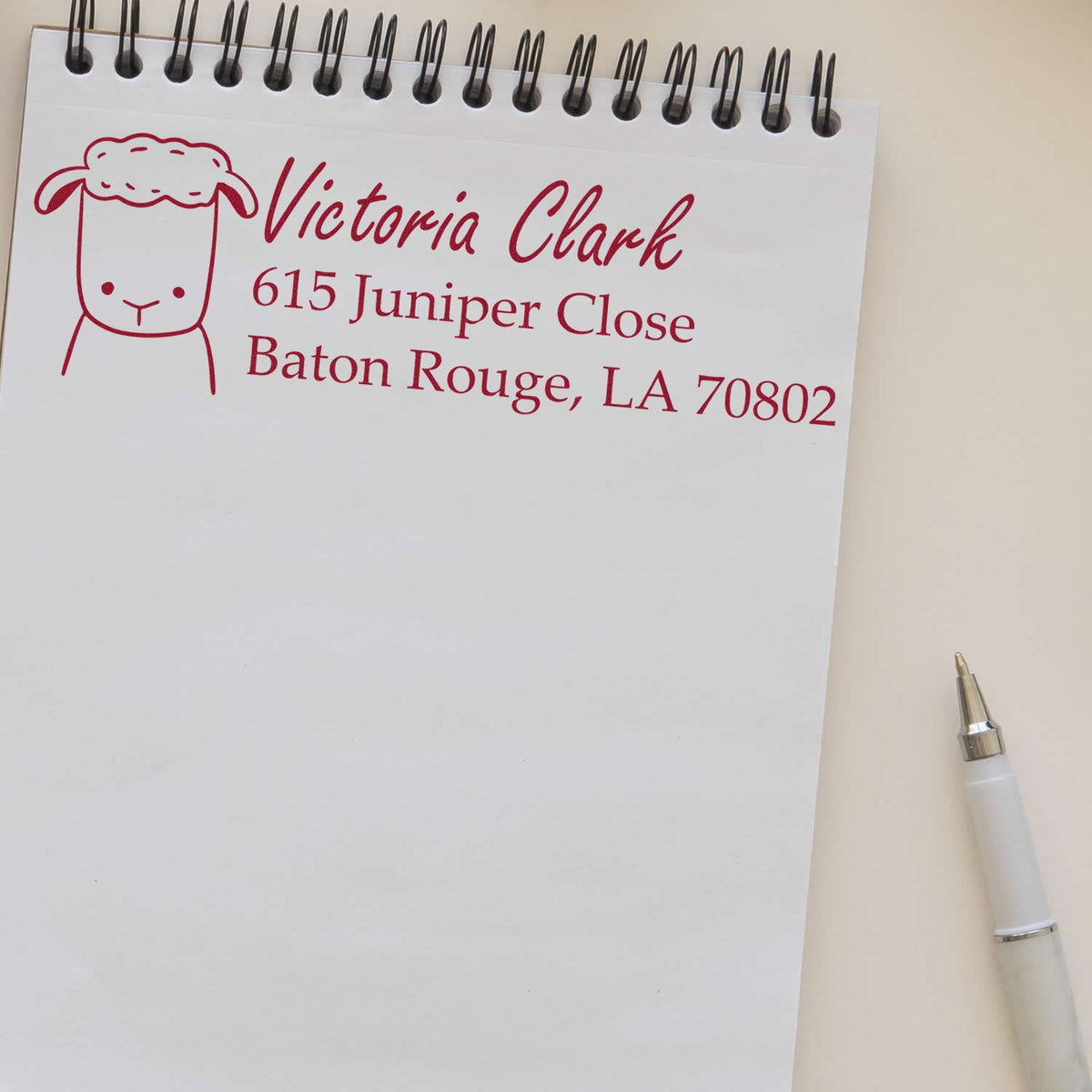 Custom address rubber stamp with sheep logo for Victoria Clark, Baton Rouge, LA, stamped on a notepad.