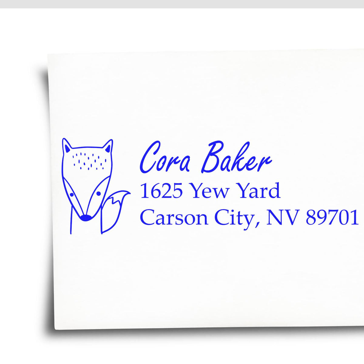 Custom blue return address rubber stamp with fox logo for Cora Baker, 1625 Yew Yard, Carson City, NV 89701.