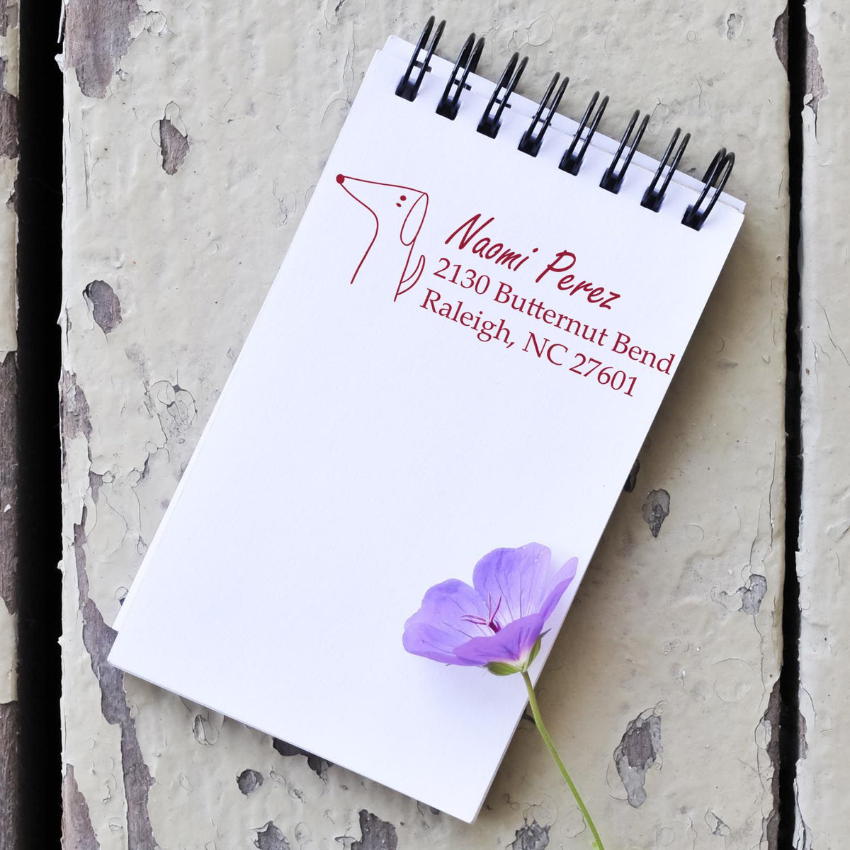 Custom rubber stamp return address for Naomi Perez with dog logo and Raleigh, NC address on notepad.