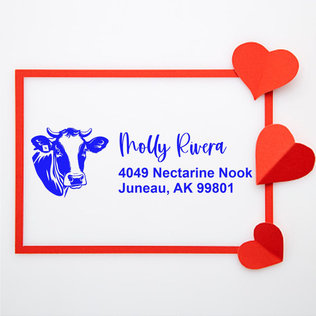 Custom rubber address stamp with cow logo, Molly Rivera, and Juneau, AK 99801, accented with red heart corners.