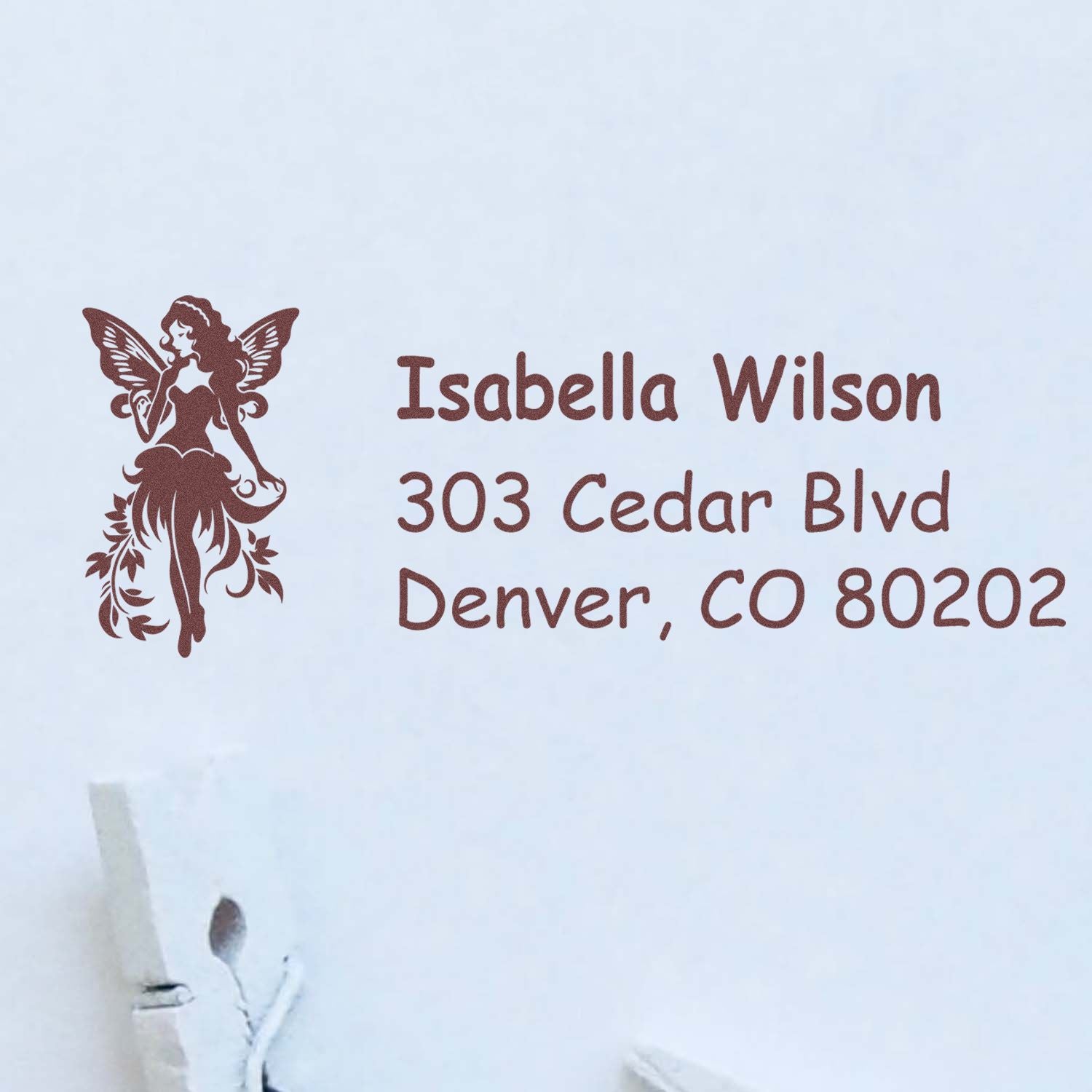 Personalized rubber return address stamp with fairy logo for Isabella Wilson, 303 Cedar Blvd, Denver, CO 80202.
