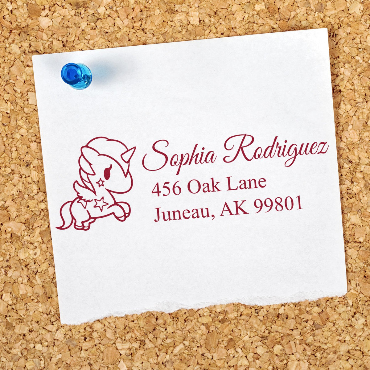 Custom unicorn return address rubber stamp on white envelope with Sophia Rodriguez, Juneau, AK address pinned to corkboard.