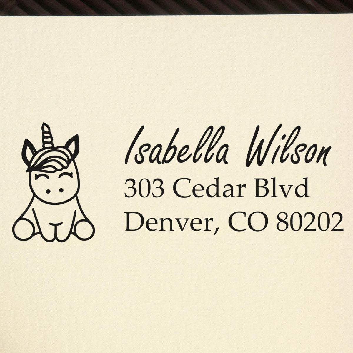 Custom rubber stamp with unicorn icon and return address for Isabella Wilson, 303 Cedar Blvd, Denver, CO 80202.