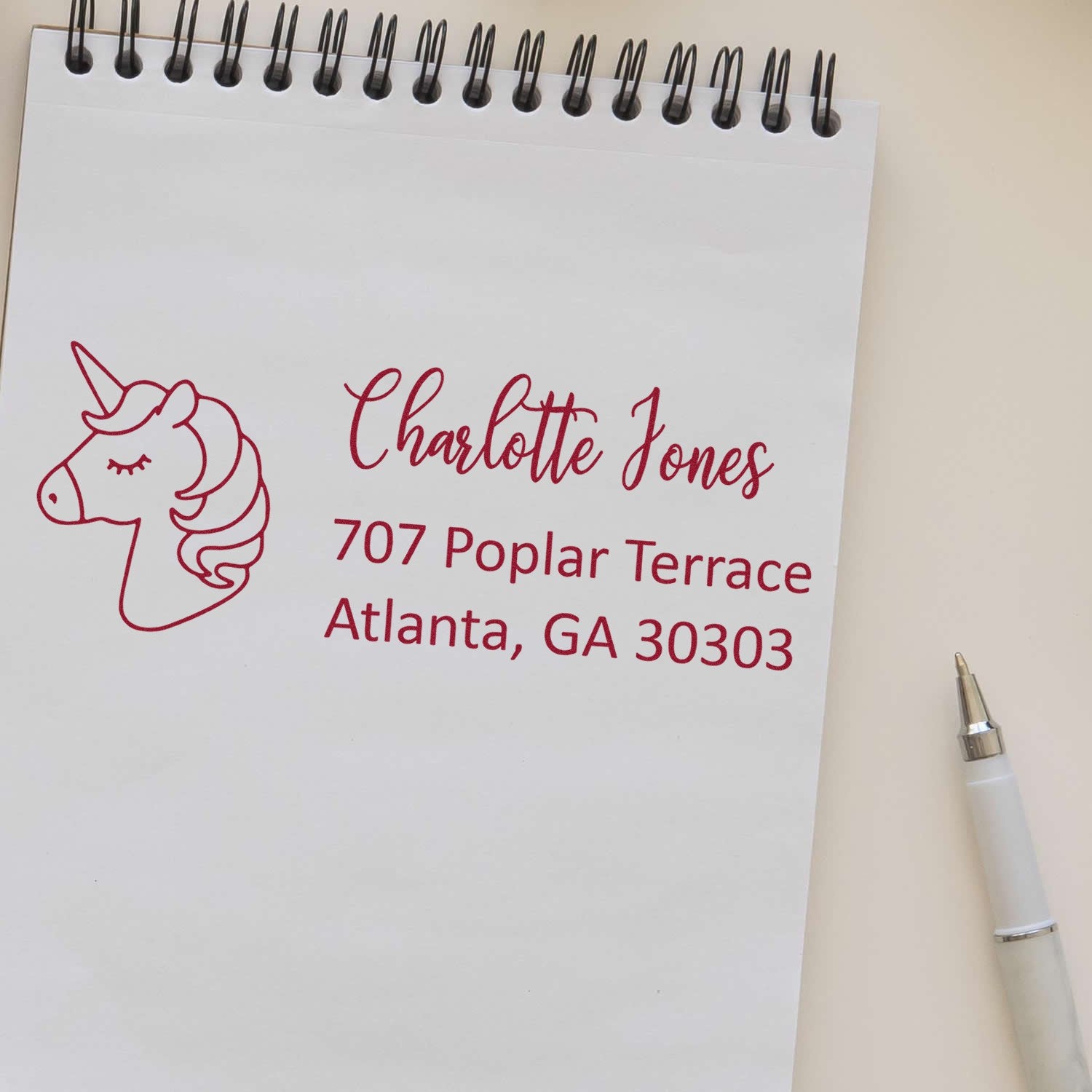 Custom unicorn return address rubber stamp with name and Atlanta, GA address in red ink on a notepad