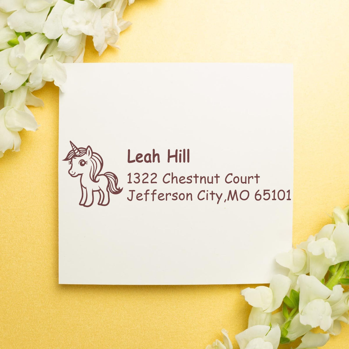 Custom unicorn return address rubber stamp on stationery with a floral wedding-style background.