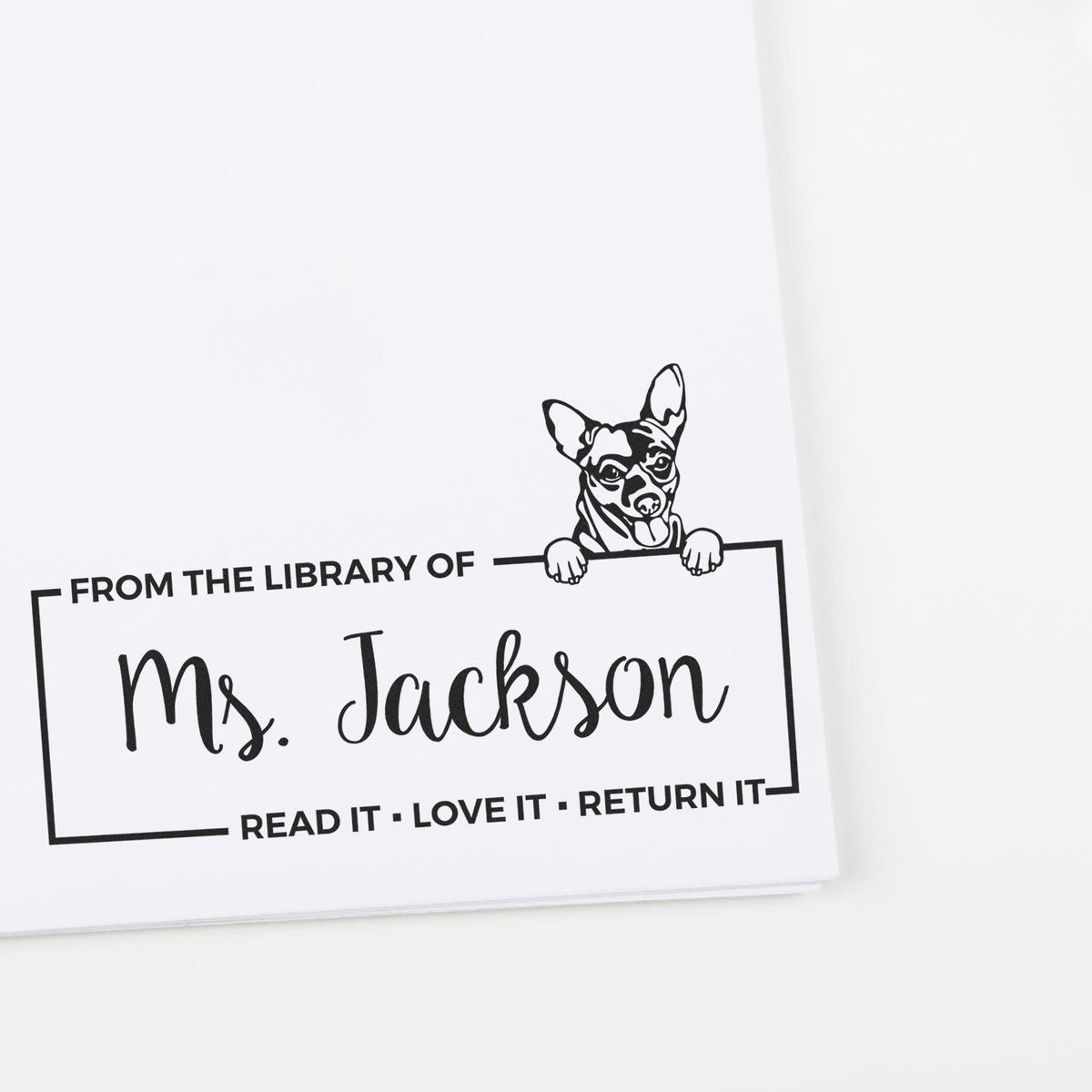 Personalized library rubber stamp with dog design and From the Library of Ms. Jackson bookplate return message.